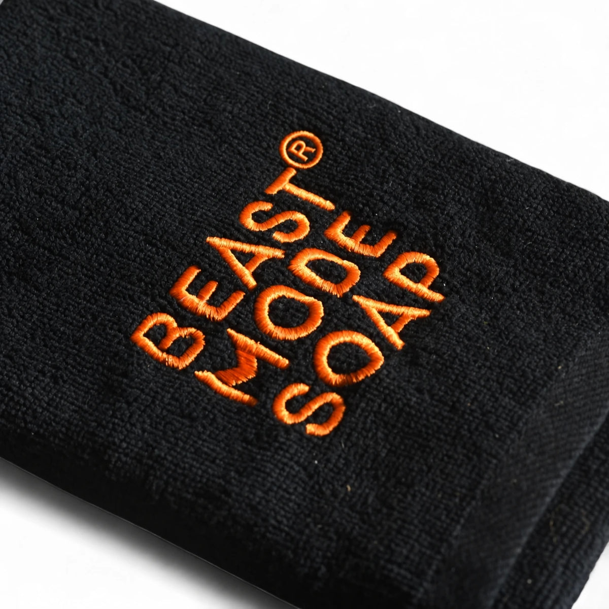 Close-up of orange Beast Mode Soap embroidery and registered trademark symbol on a black cotton towel